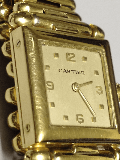 Vintage Cartier Square Watch in yellow gold, circa 1950, featuring a champagne dial, Arabic numerals, cabochon sapphire crown, and bullet-link bracelet.