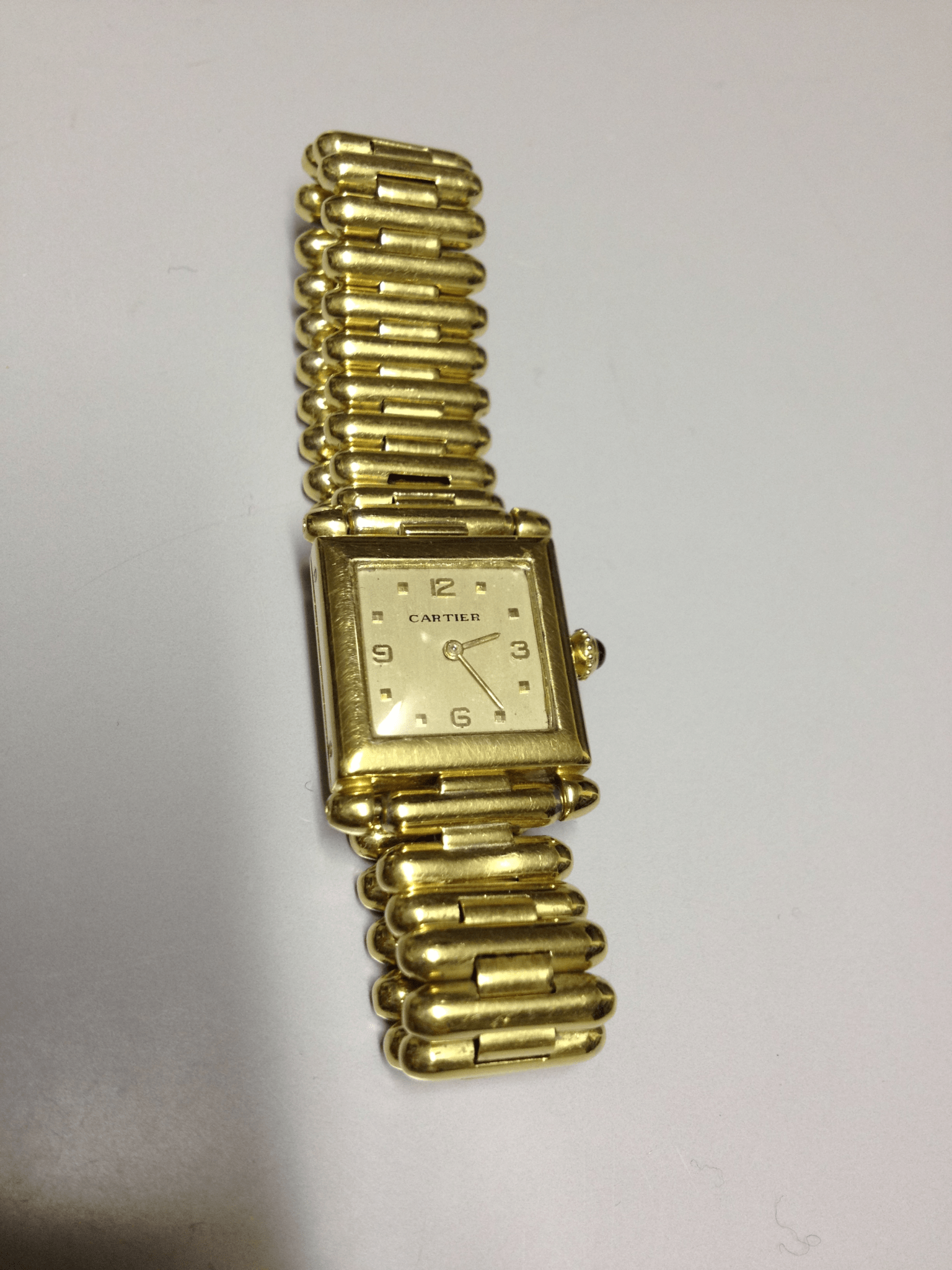 Vintage Cartier Square Watch in yellow gold, circa 1950, featuring a champagne dial, Arabic numerals, cabochon sapphire crown, and bullet-link bracelet.