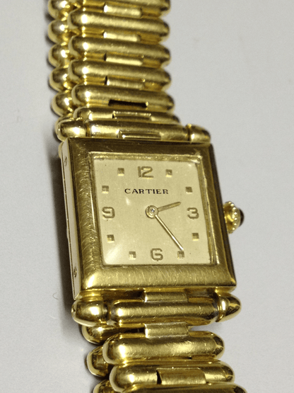 Vintage Cartier Square Watch in yellow gold, circa 1950, featuring a champagne dial, Arabic numerals, cabochon sapphire crown, and bullet-link bracelet.